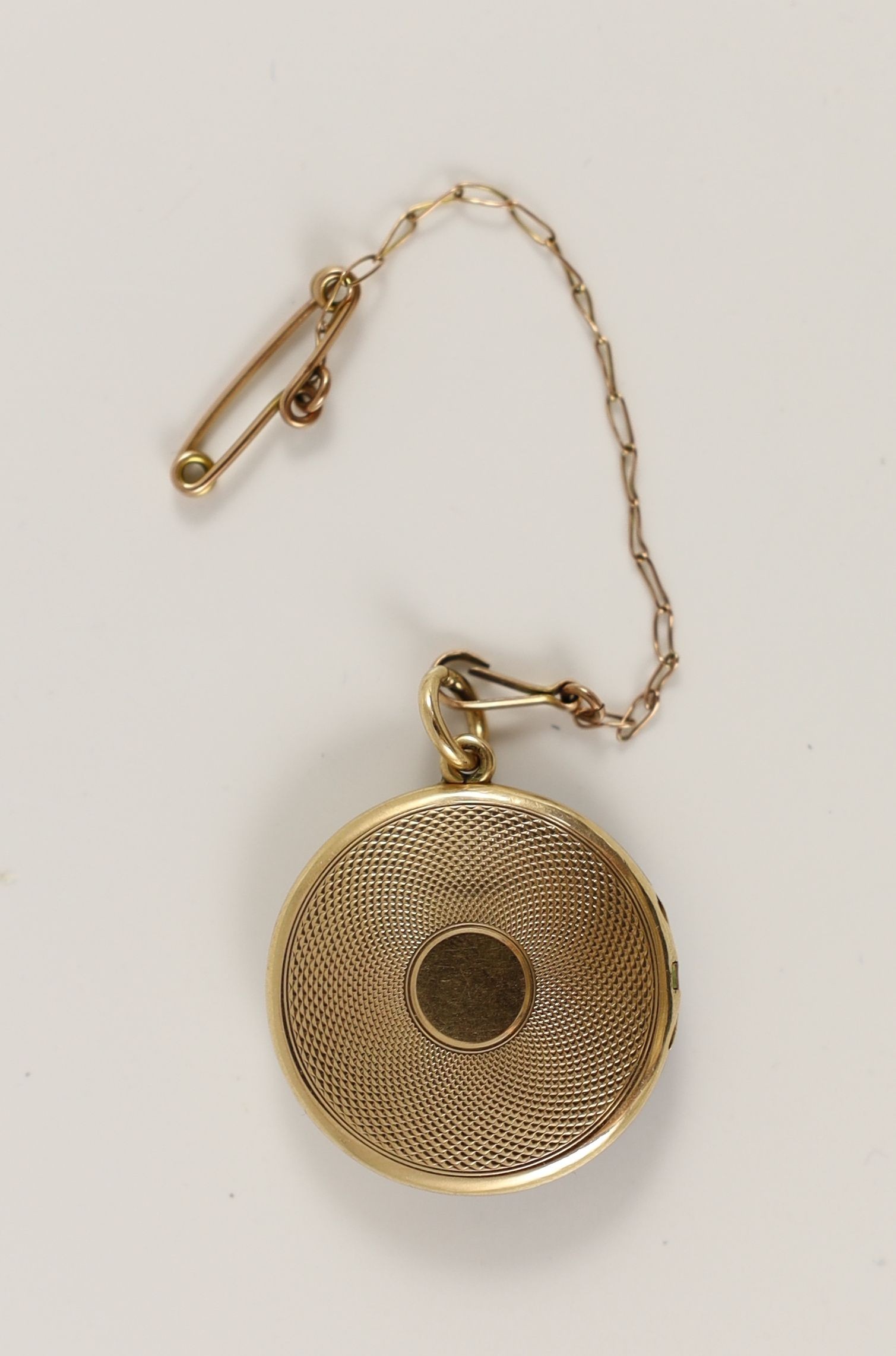An Edwardian engine turned gold, blue guilloche enamel with gilded scrolls and diamond set circular pendant locket